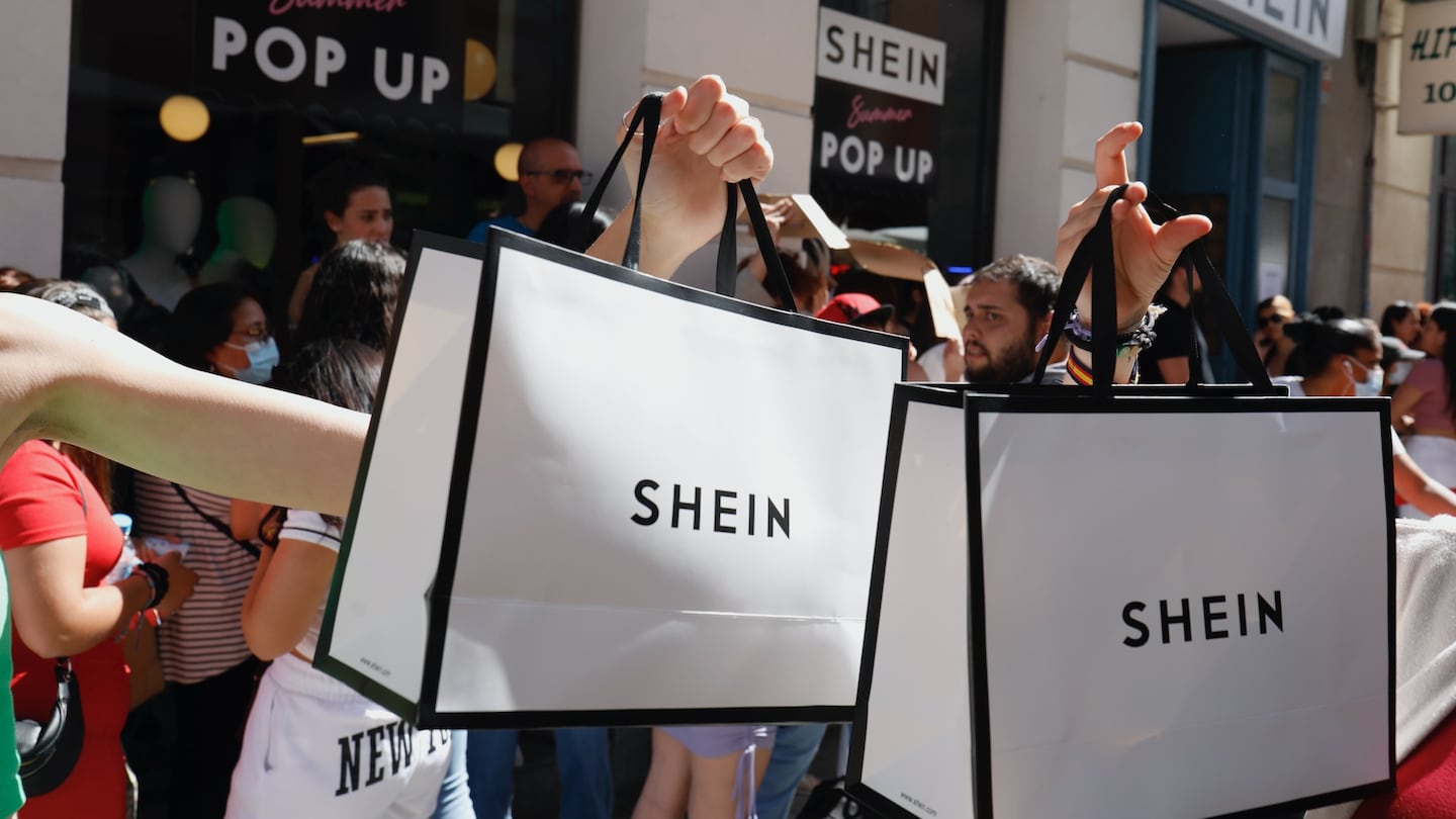 Shoppers hold up Shein bags outside a pop-up for the ultra-fast-fashion giant.