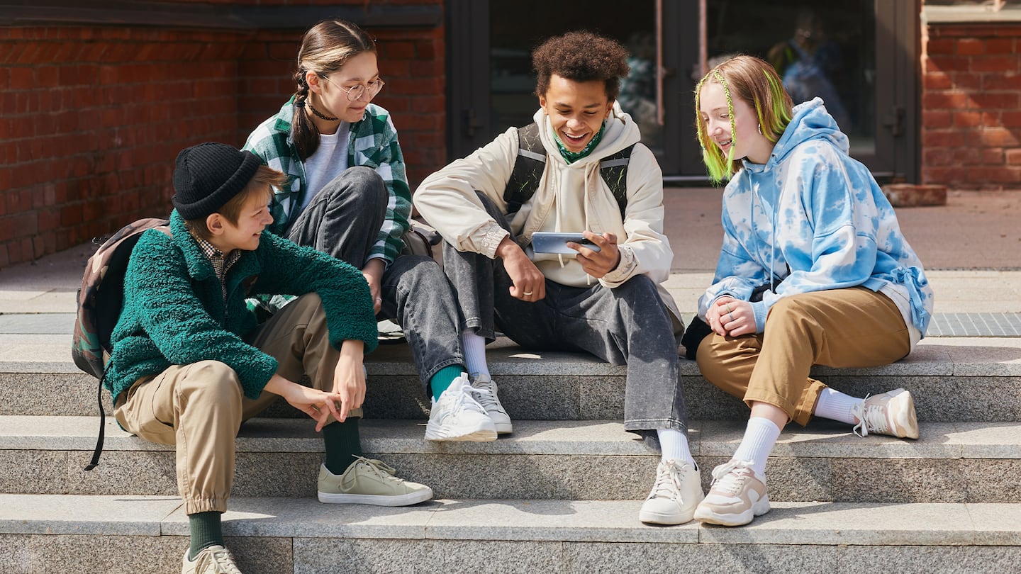 A group of young children gathered around a phone screen